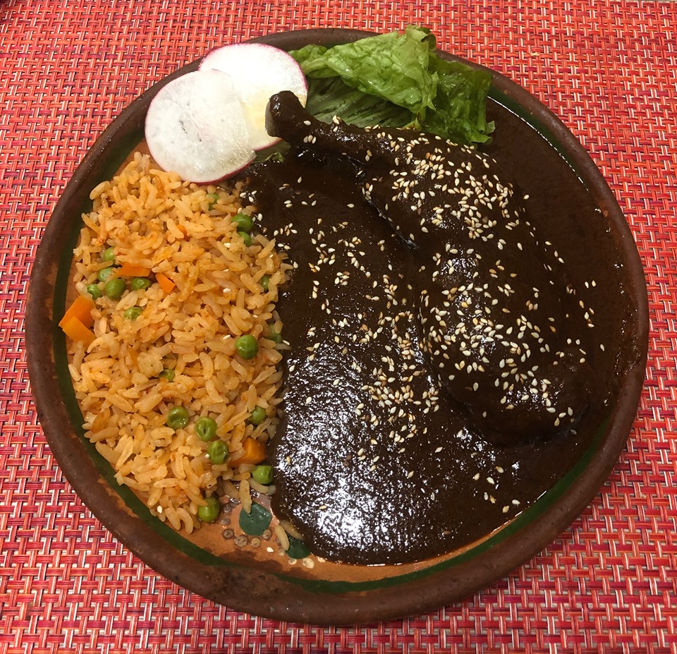 Mole con pollo servido en plato con arroz rojo